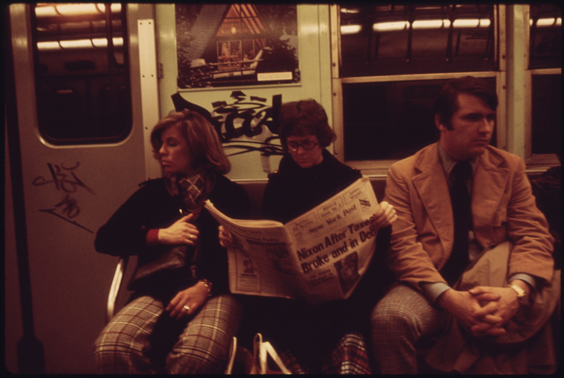 Passengers on a New York subway car, each absorbed in a newspaper